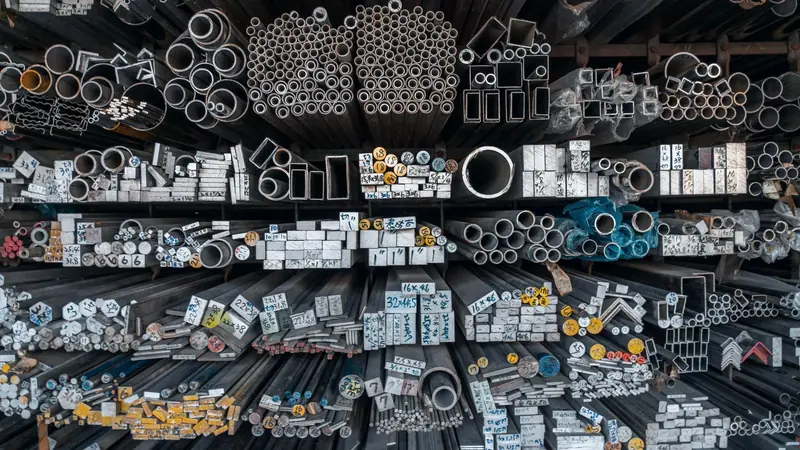 Barres, tubes et cornières en métal rangés en rayonnage, vus de face, avec des étiquettes de dimensions
