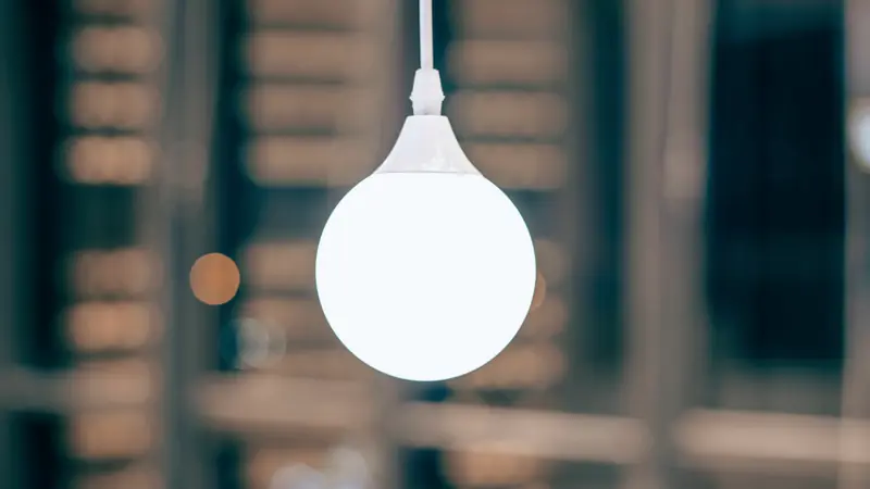 Suspension à globe blanc allumée devant un arrière-plan flou