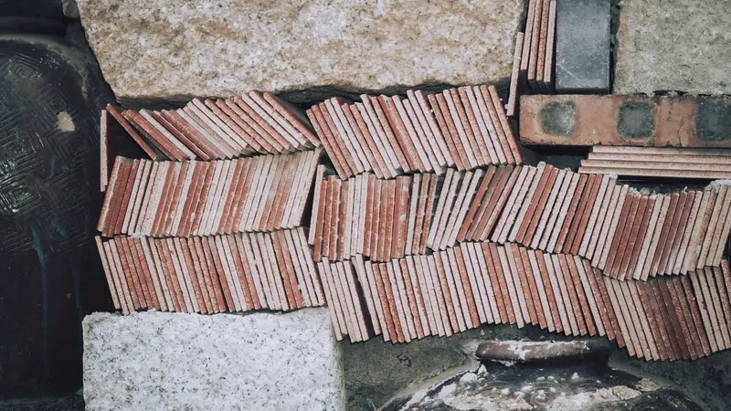 Carreaux de terre cuite rouges rangés sur la tranche entre des blocs de granit