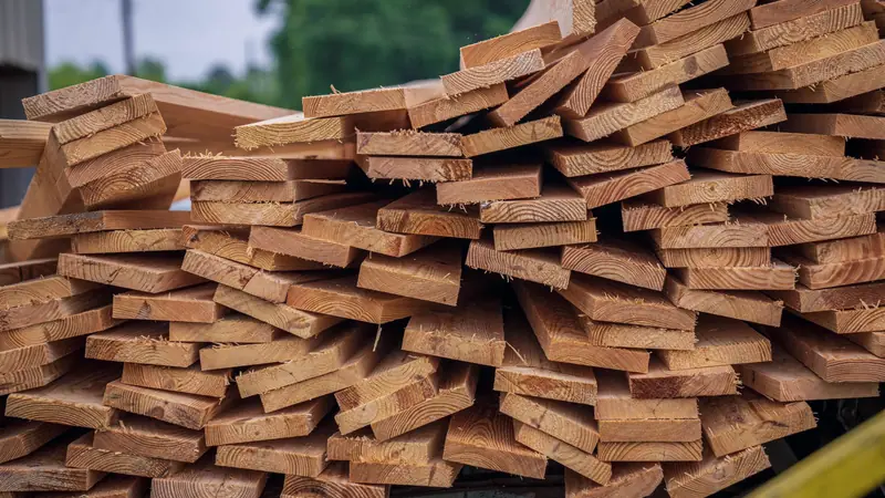 Pile de planches de bois brut fraîchement sciées, stockées en extérieur