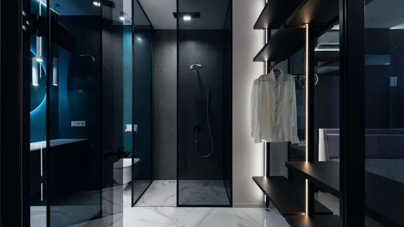 Douche à l'italienne fermée par des parois vitrées à cadre noir, murs en grandes plaques gris anthracite et sol en marbre blanc