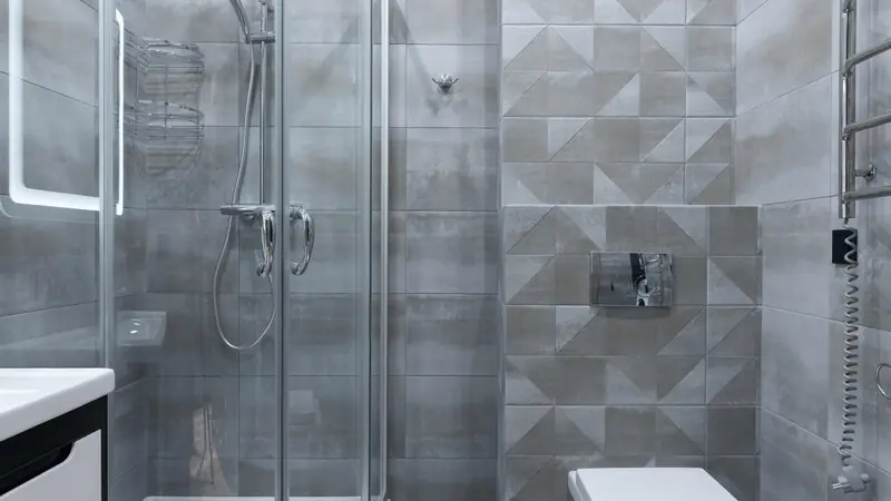 Petite salle de bain grise avec cabine de douche vitrée, carrelage à motifs géométriques et WC suspendu