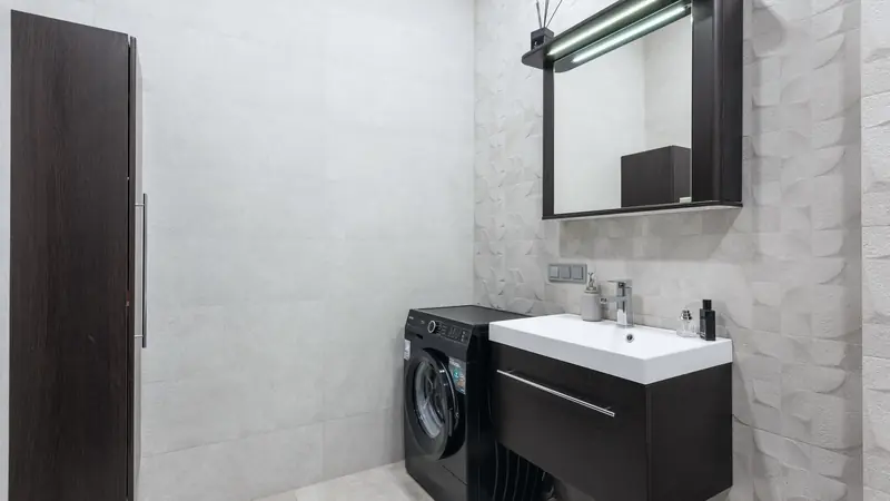Meuble suspendu en bois foncé avec plan vasque blanc moulé, mitigeur chromé et armoire de toilette éclairée